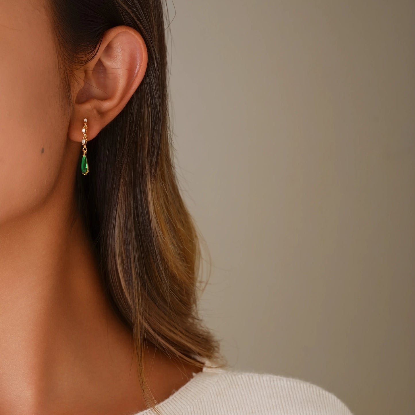 Model wearing emerald dangle diamond clip-on earrings for a glamorous evening look.