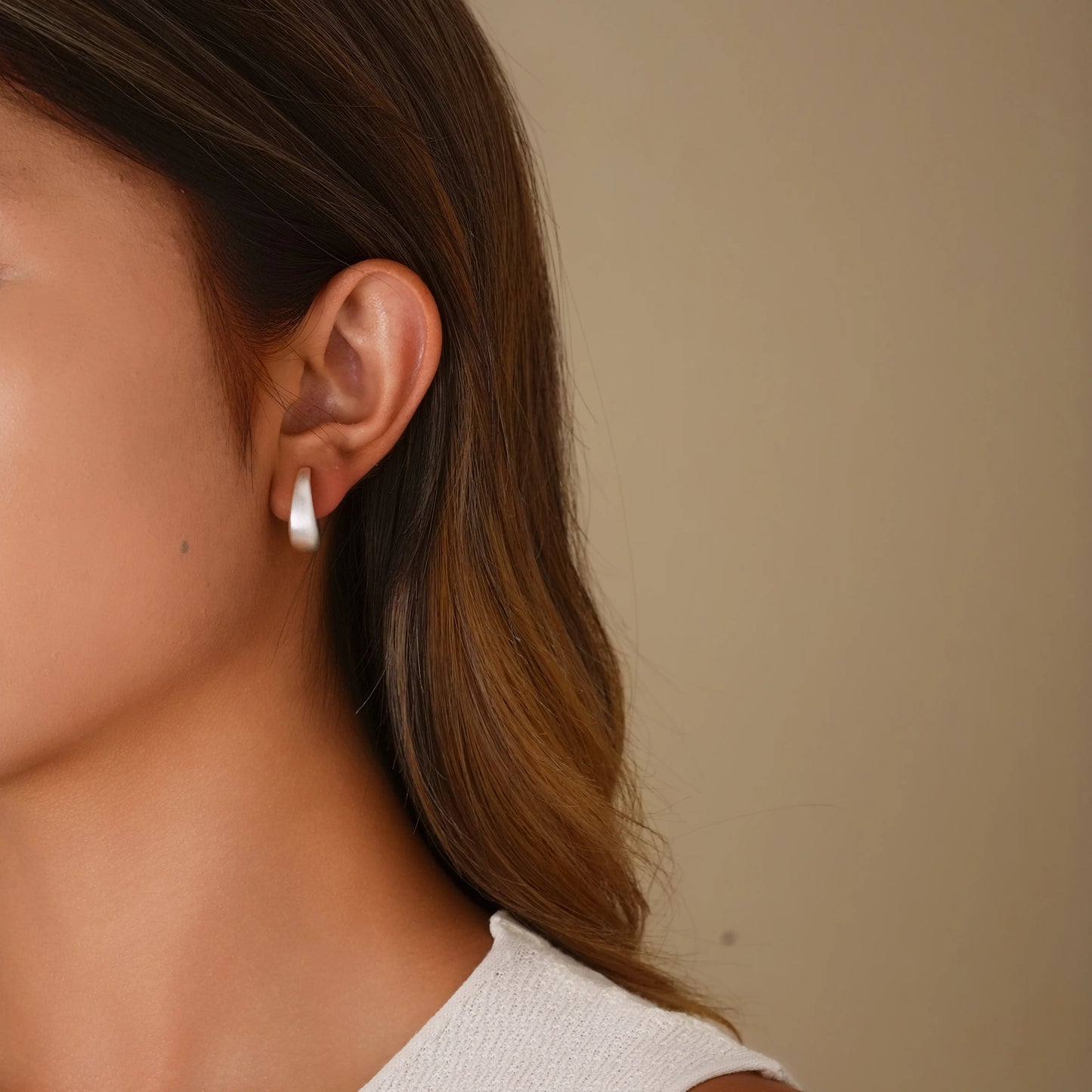 Model wearing matte silver minimalist hoops for a sophisticated, modern office look.