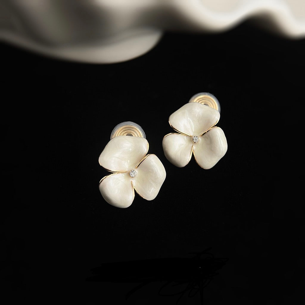 Delicate white flower earrings styled aesthetically next to a fresh cup of tea and a silk ribbon for a soft, feminine vibe