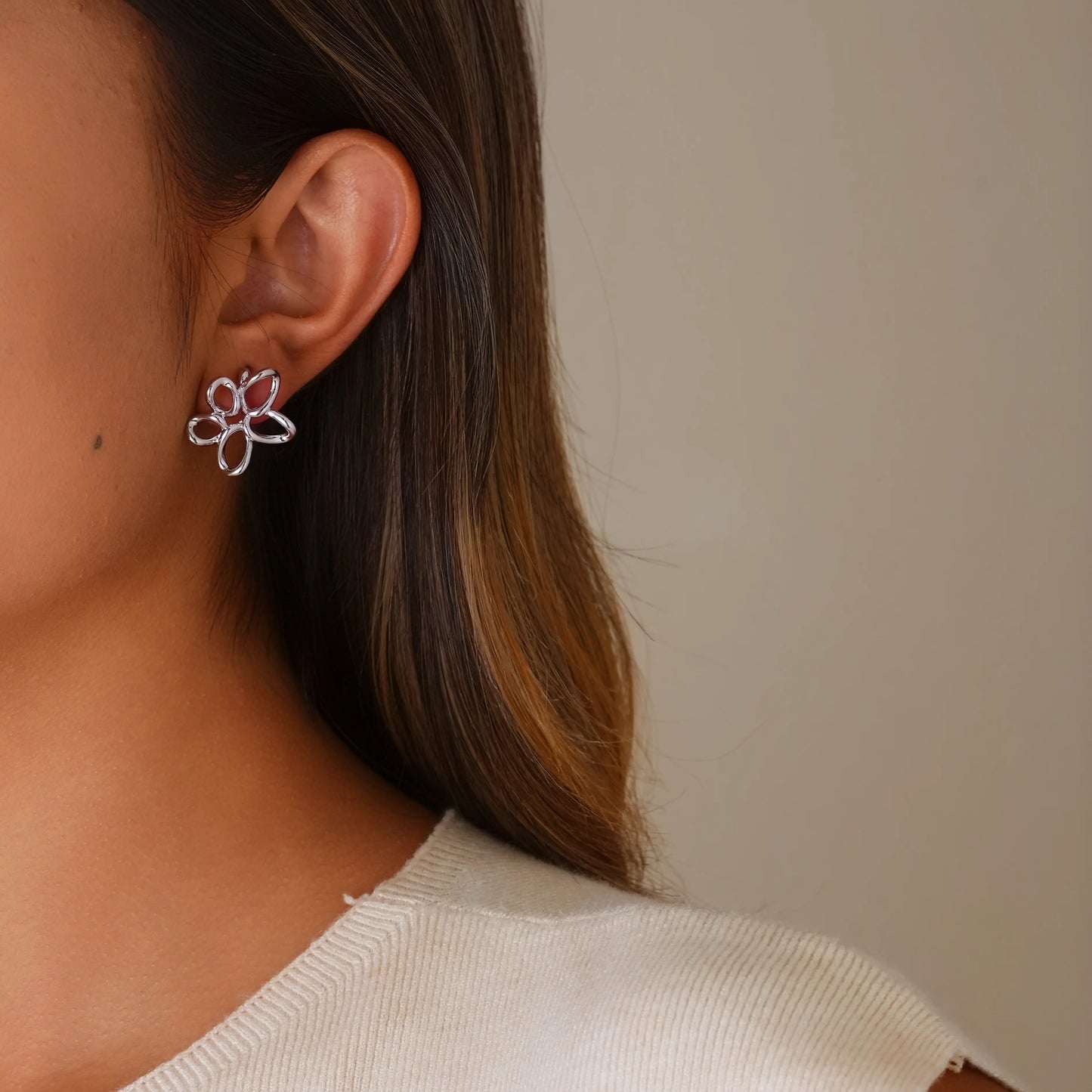 Model styling silver twisted wire flower earrings for a clean, minimalist aesthetic.