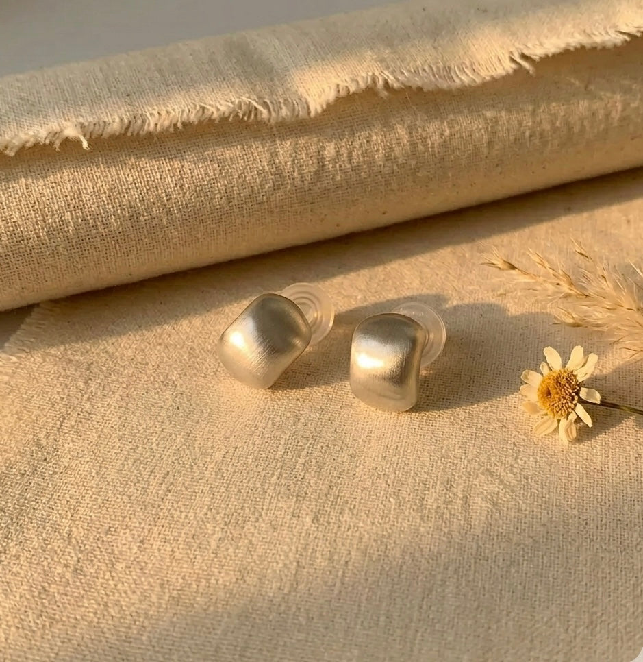 Close-up of the discreet and comfortable clip-on mechanism on a matte silver stud earring