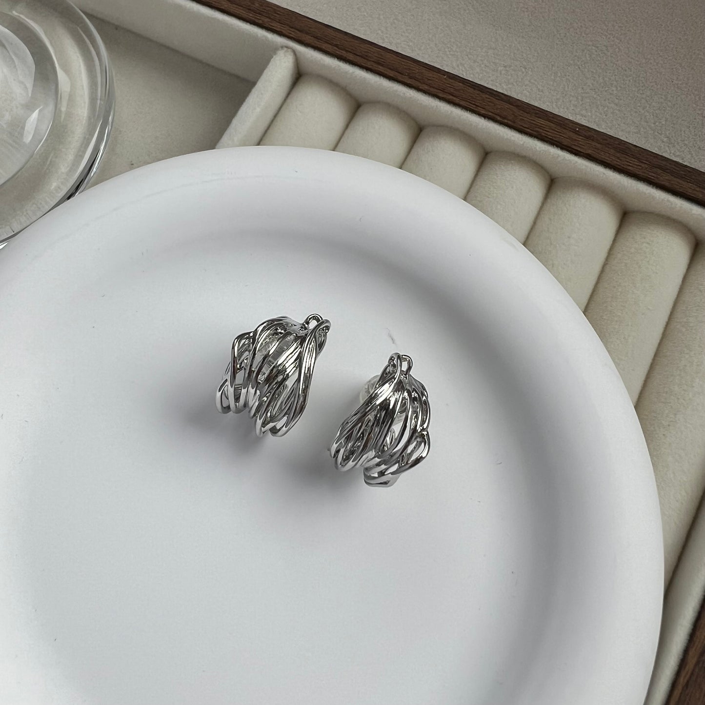Front view of a matching pair of silver wide hoop clip-on earrings arranged side-by-side, showing the symmetrical bold shape and polished surface.