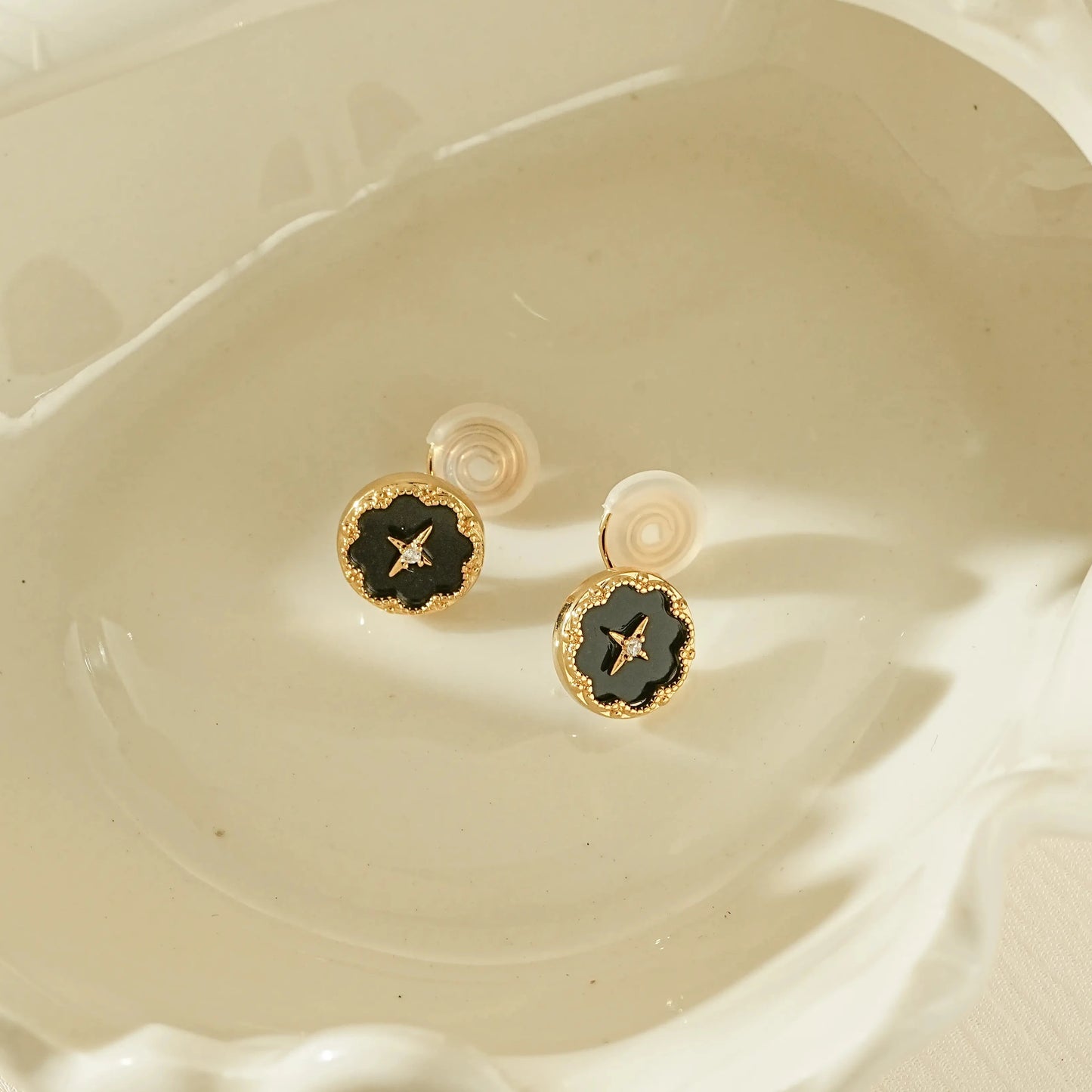 Vintage style black round clip-on earrings with a gold star and diamond center.