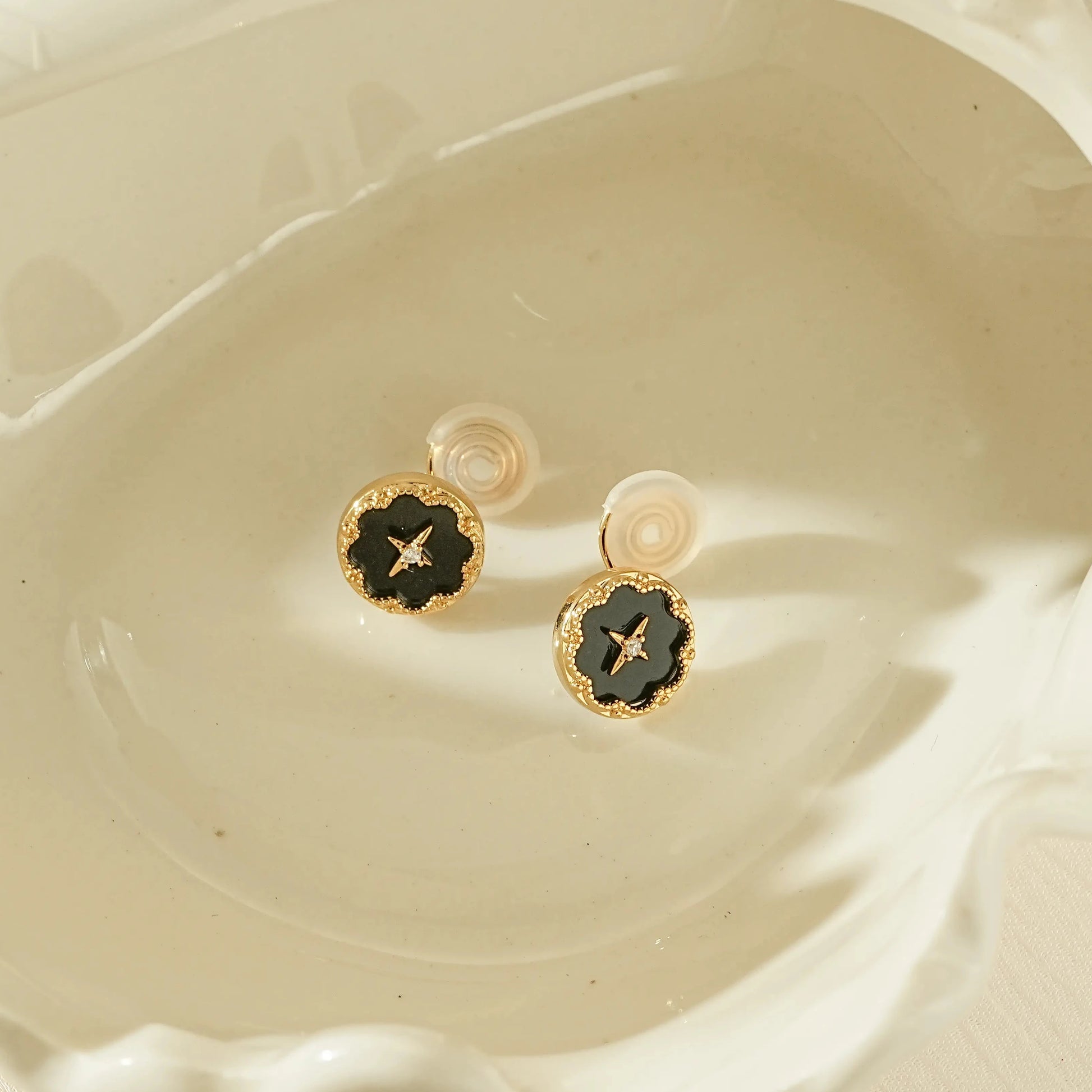 Vintage style black round clip-on earrings with a gold star and diamond center.