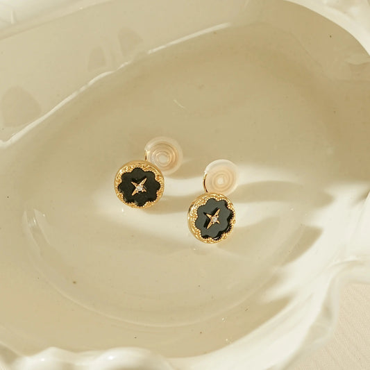 Vintage style black round clip-on earrings with a gold star and diamond center.