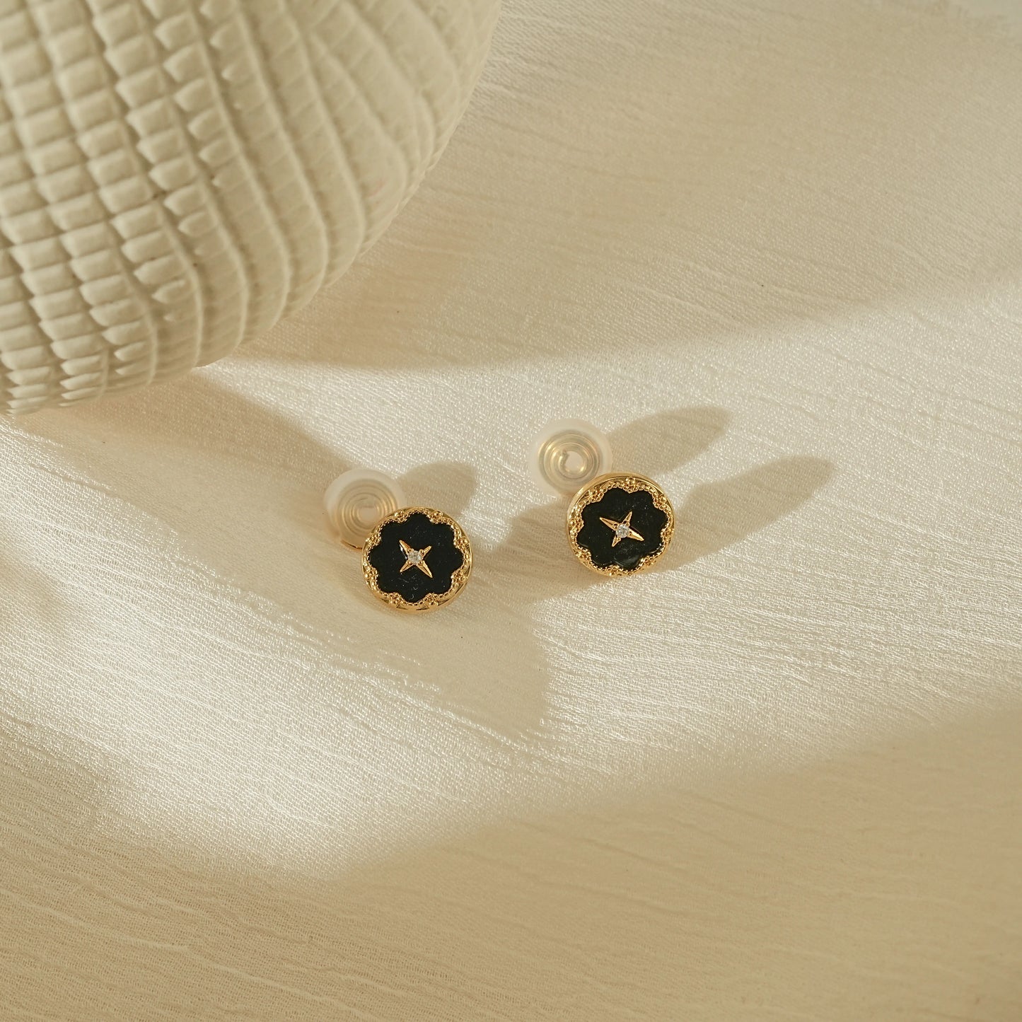Elegant celestial noir vintage star earrings on a warm, creamy background.
