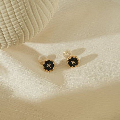 Elegant celestial noir vintage star earrings on a warm, creamy background.