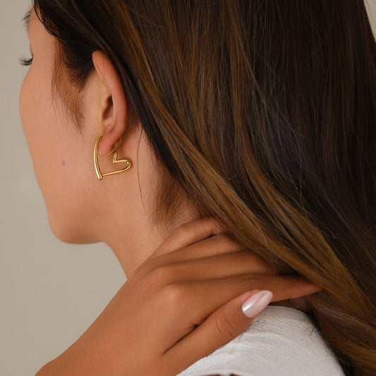 Close-up of model wearing 18k gold chunky heart hoop clip-ons, illustrating the secure and realistic "pierced" fit.
