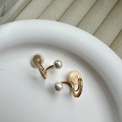 Gold hoop clip-on earrings with pearl drops resting on a branded jewellery display card.