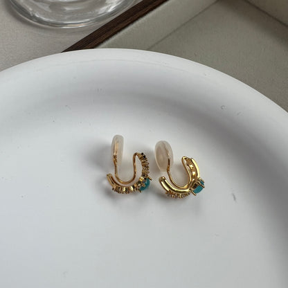 Back view of a mini gold double hoop earring showing the invisible comfort resin clip mechanism for non-pierced ears.