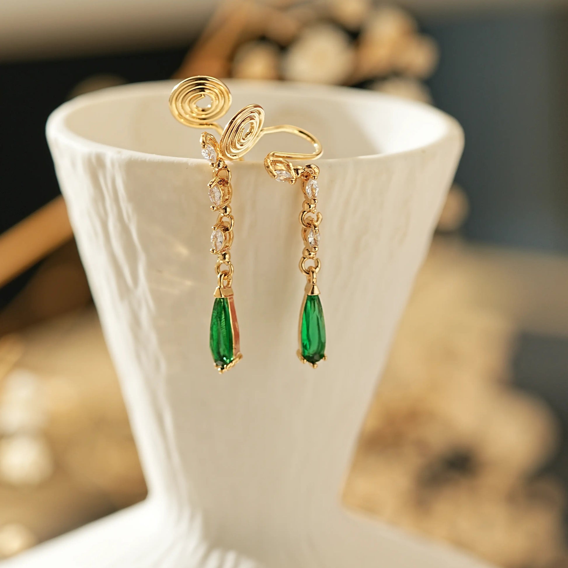 Close-up of the May birthstone emerald and diamond detail on gold clips.