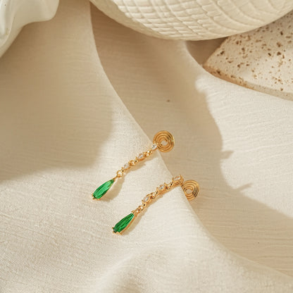Luxury emerald and gold dangle earrings for non-pierced ears on a creamy background.