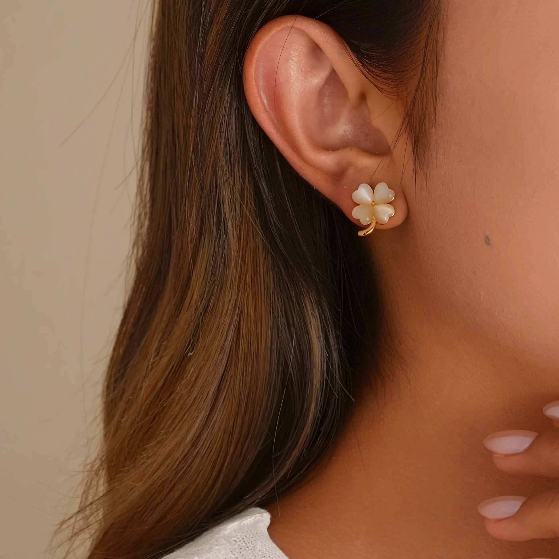 Close-up of model styling the iridescent moonstone clover earrings, showing the secure fit.