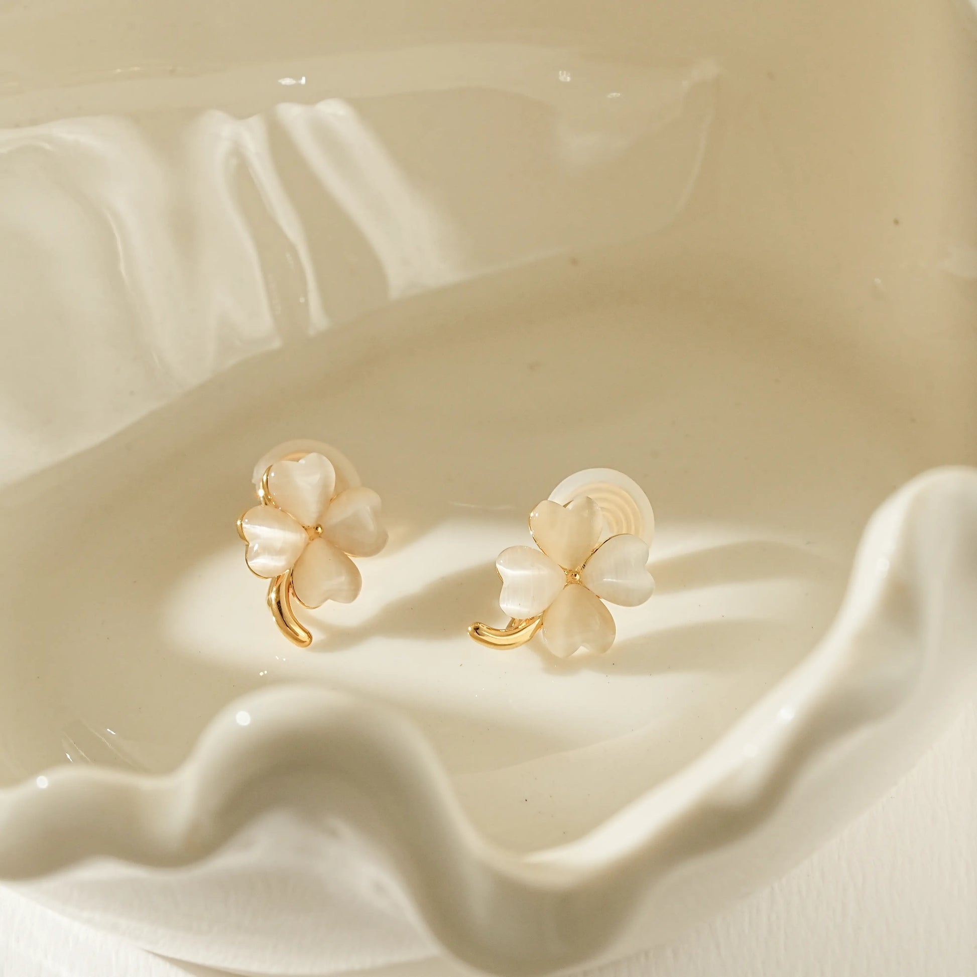 Close-up of the iridescent moonstone inlay on gold four leaf clover clip-ons.