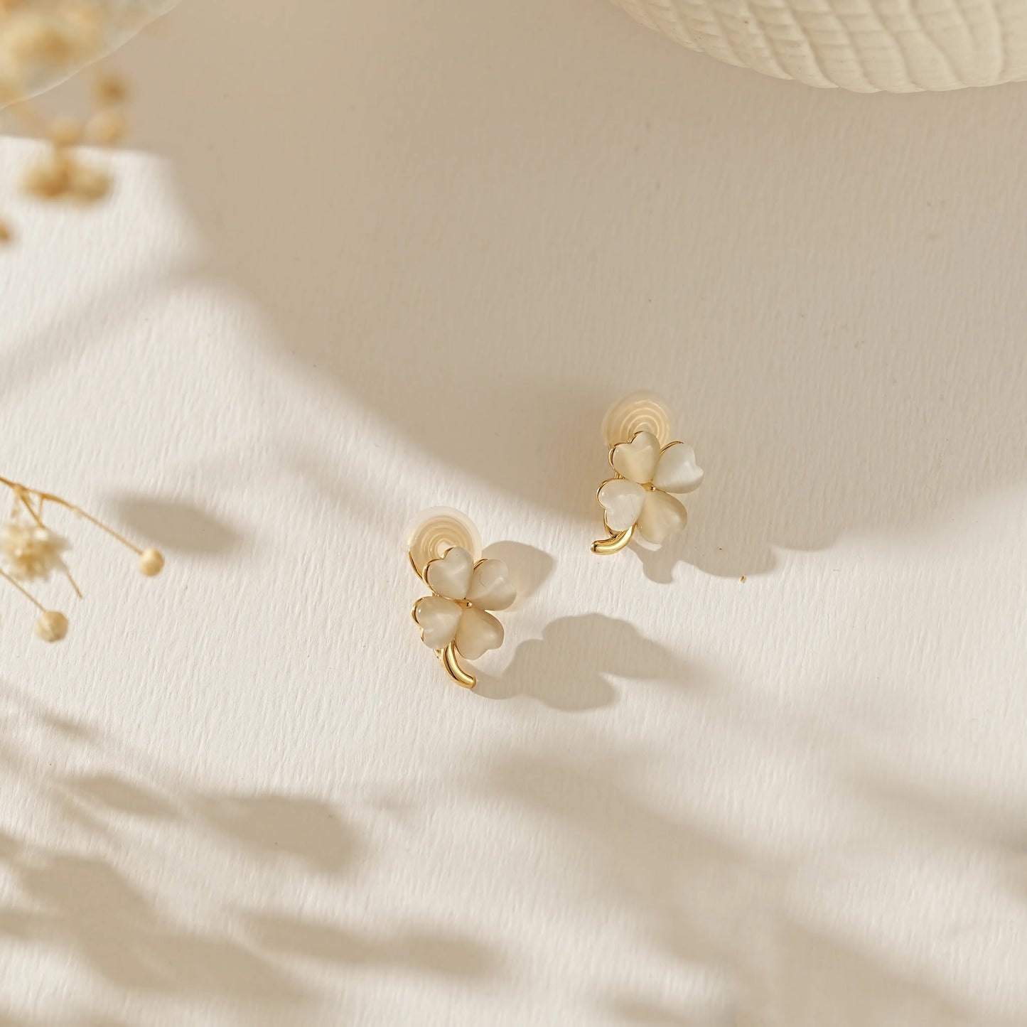 Lucky four leaf clover moonstone earrings for June birthdays on a creamy background.