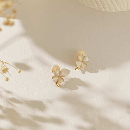 Lucky four leaf clover moonstone earrings for June birthdays on a creamy background.