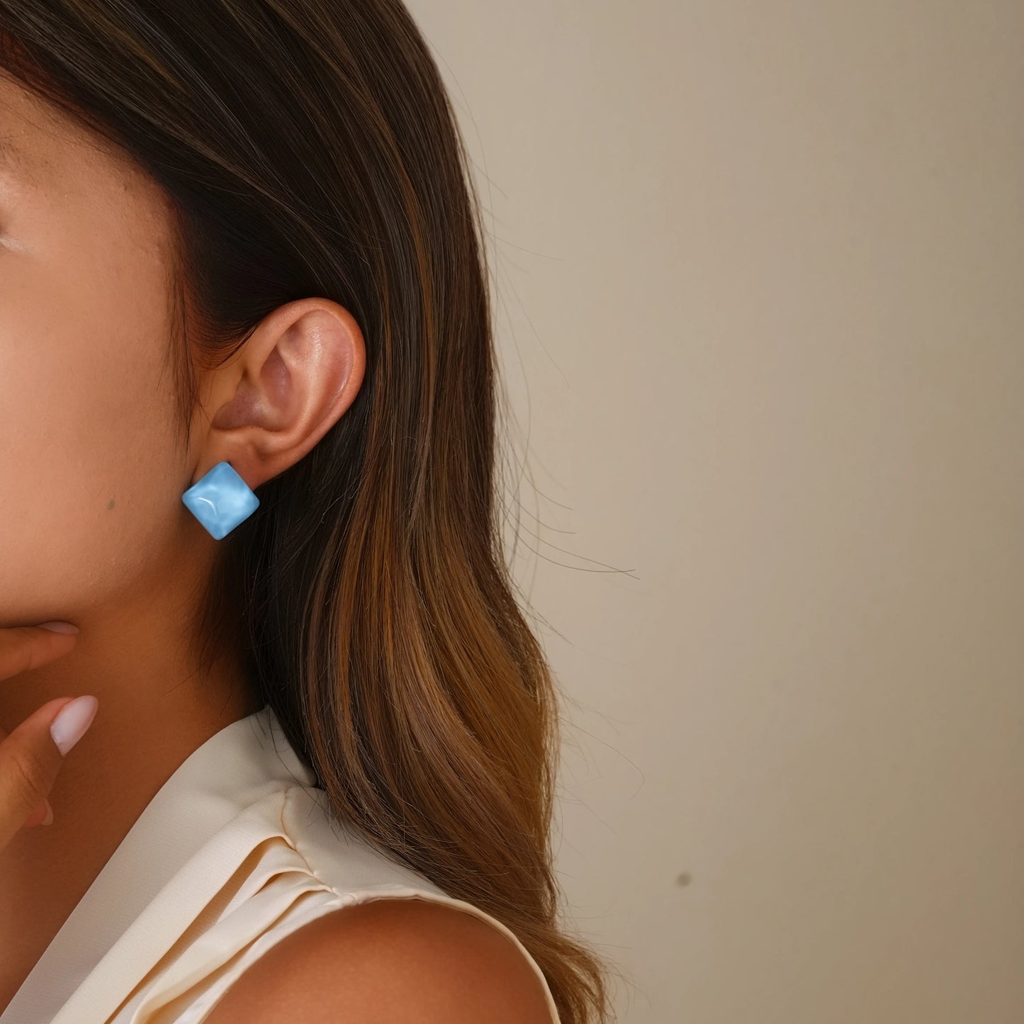Model wearing ice blue glass cube clip-ons for a modern, architectural jewelry look.