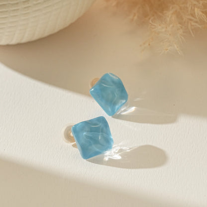 Contemporary blue glass cube earrings for unpierced ears on a clean, bright background.