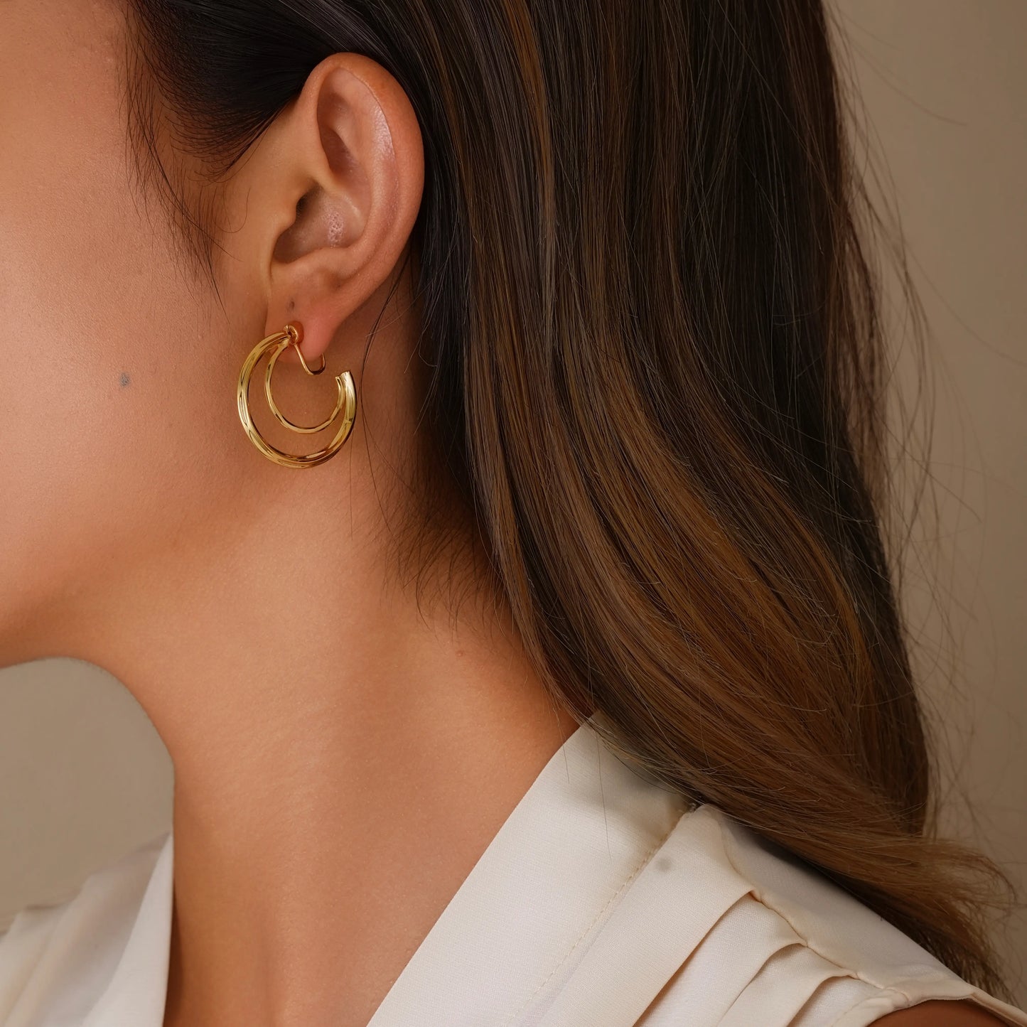 Model wearing gold lunar crescent double hoops, showing a realistic layered piercing look
