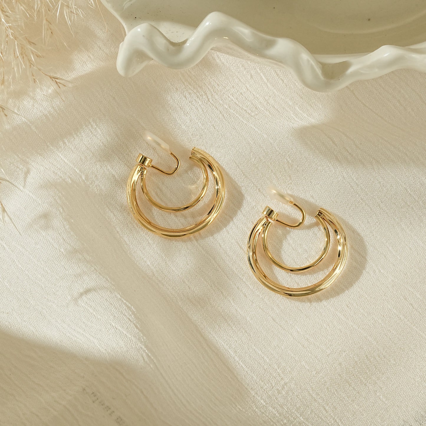 Gold chunky double hoop clip-on earrings in a half moon crescent design.