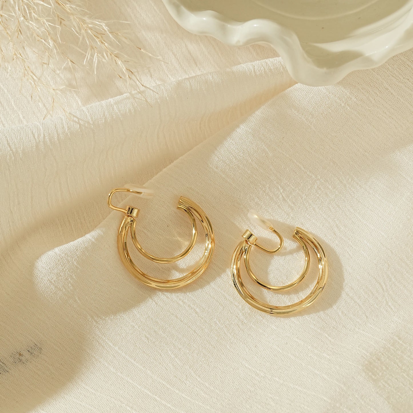 Side view of gold crescent double hoops showing the adjustable, pinch-free clip back.