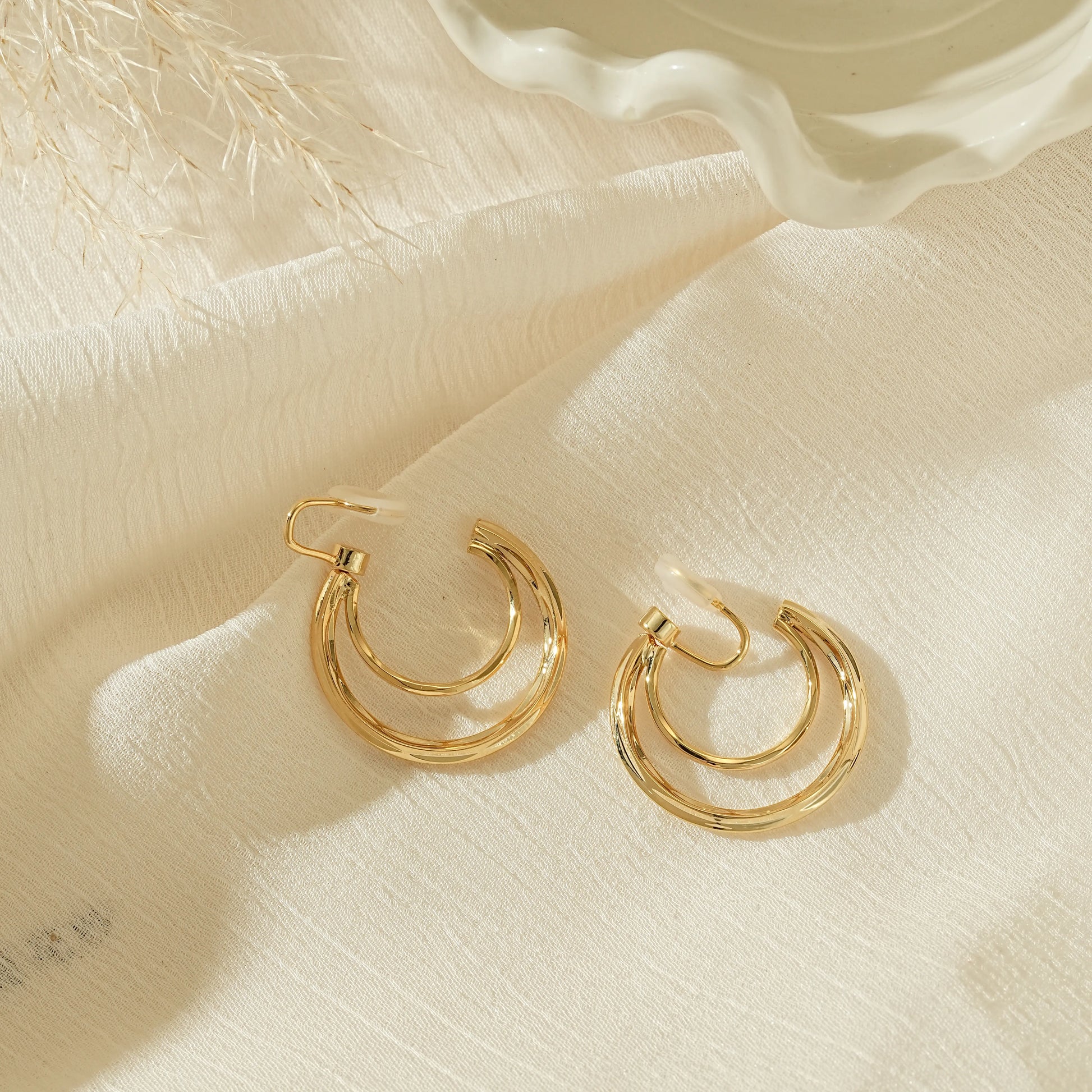 Side view of gold crescent double hoops showing the adjustable, pinch-free clip back.