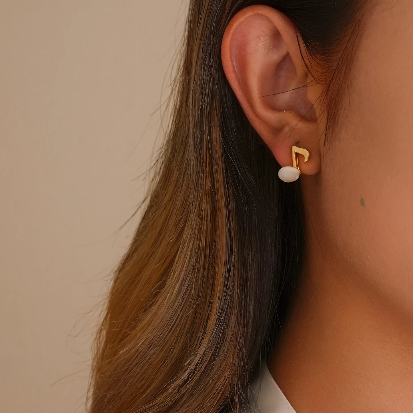 Close-up of model styling the music note earrings, showing the realistic "pierced" fit.