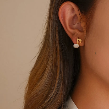 Close-up of model styling the music note earrings, showing the realistic "pierced" fit.