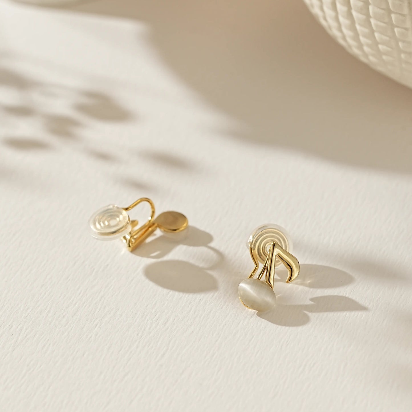 Close-up of polished gold musical note earrings for unpierced ears.