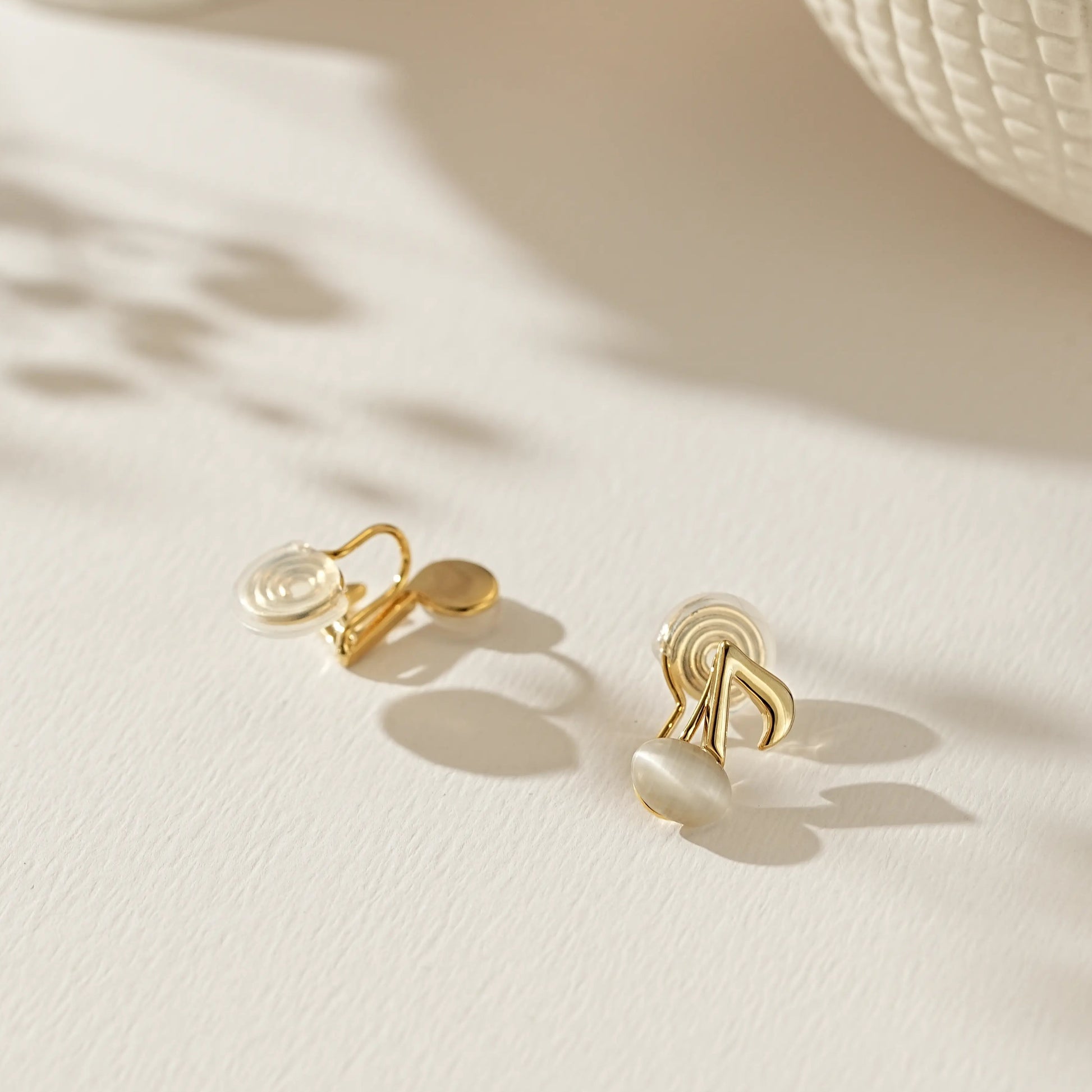 Close-up of polished gold musical note earrings for unpierced ears.