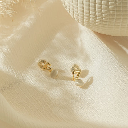 Elegant gold music note earrings for musicians, laid on a creamy background.