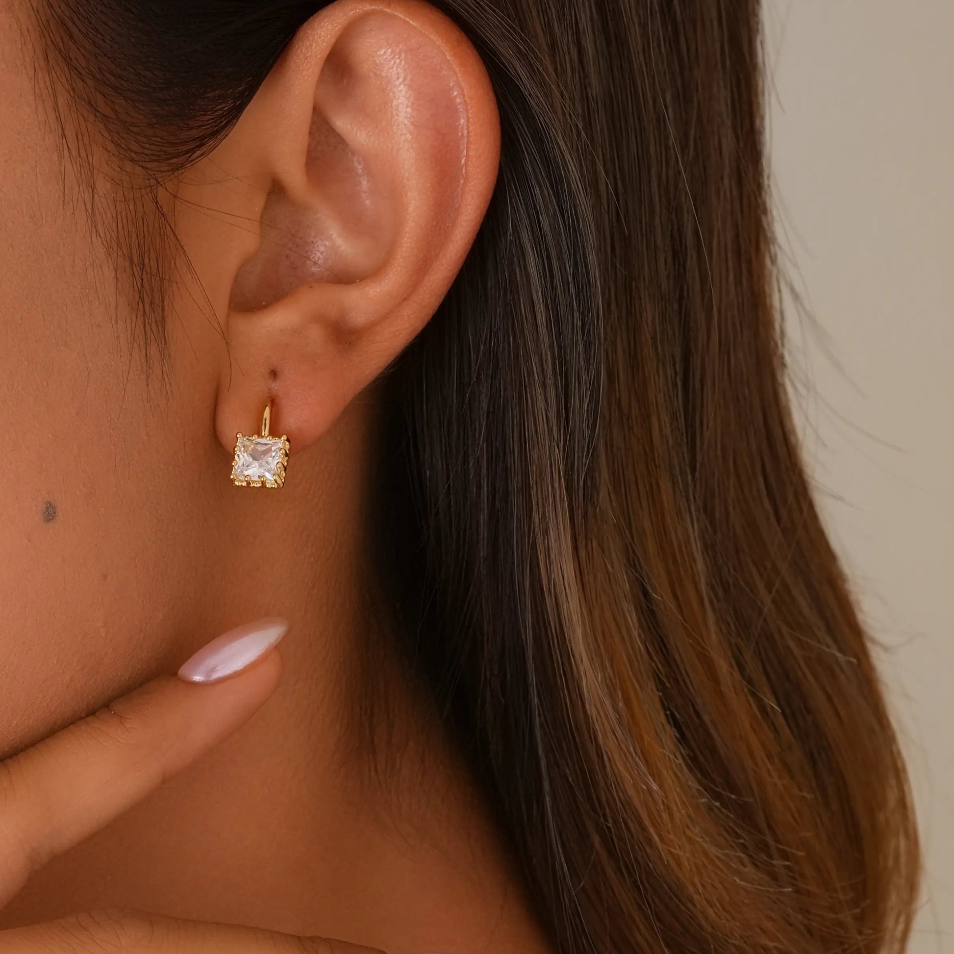 Model with unpierced ears wearing the gold princess cut clip-on studs for a classic, sophisticated look.