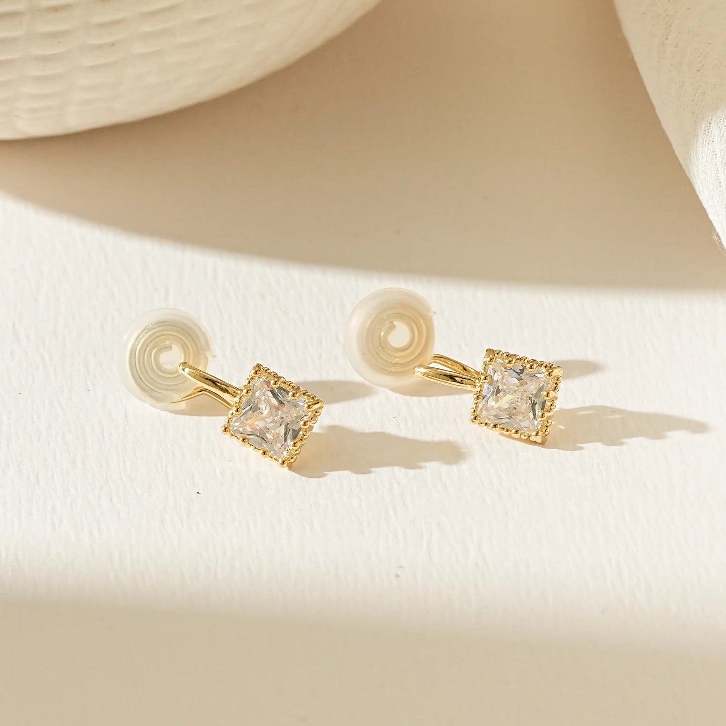 Pair of gold princess cut diamond clip-on studs, front view showing brilliant sparkle.