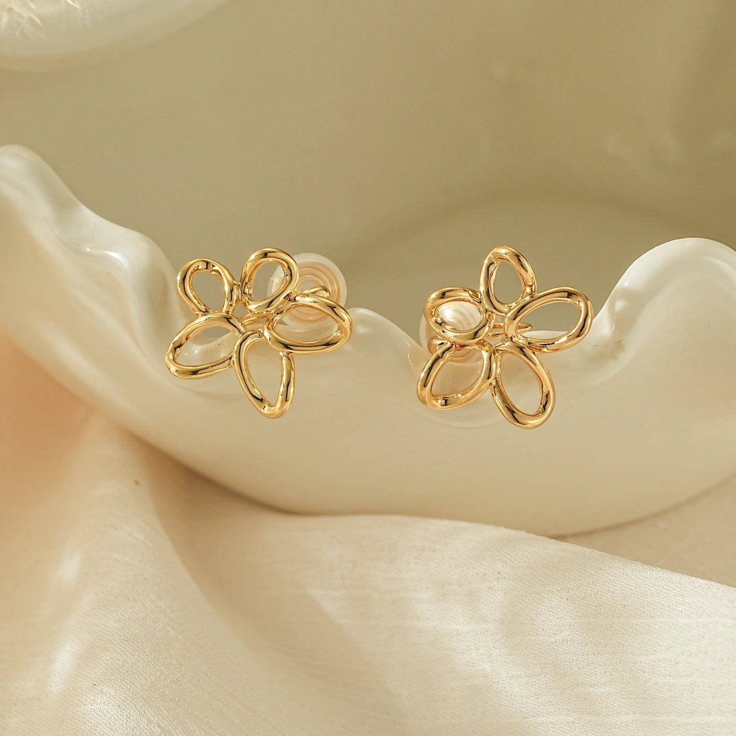 Close-up of the hand-twisted gold wire petal detail on minimalist clip-on earrings.