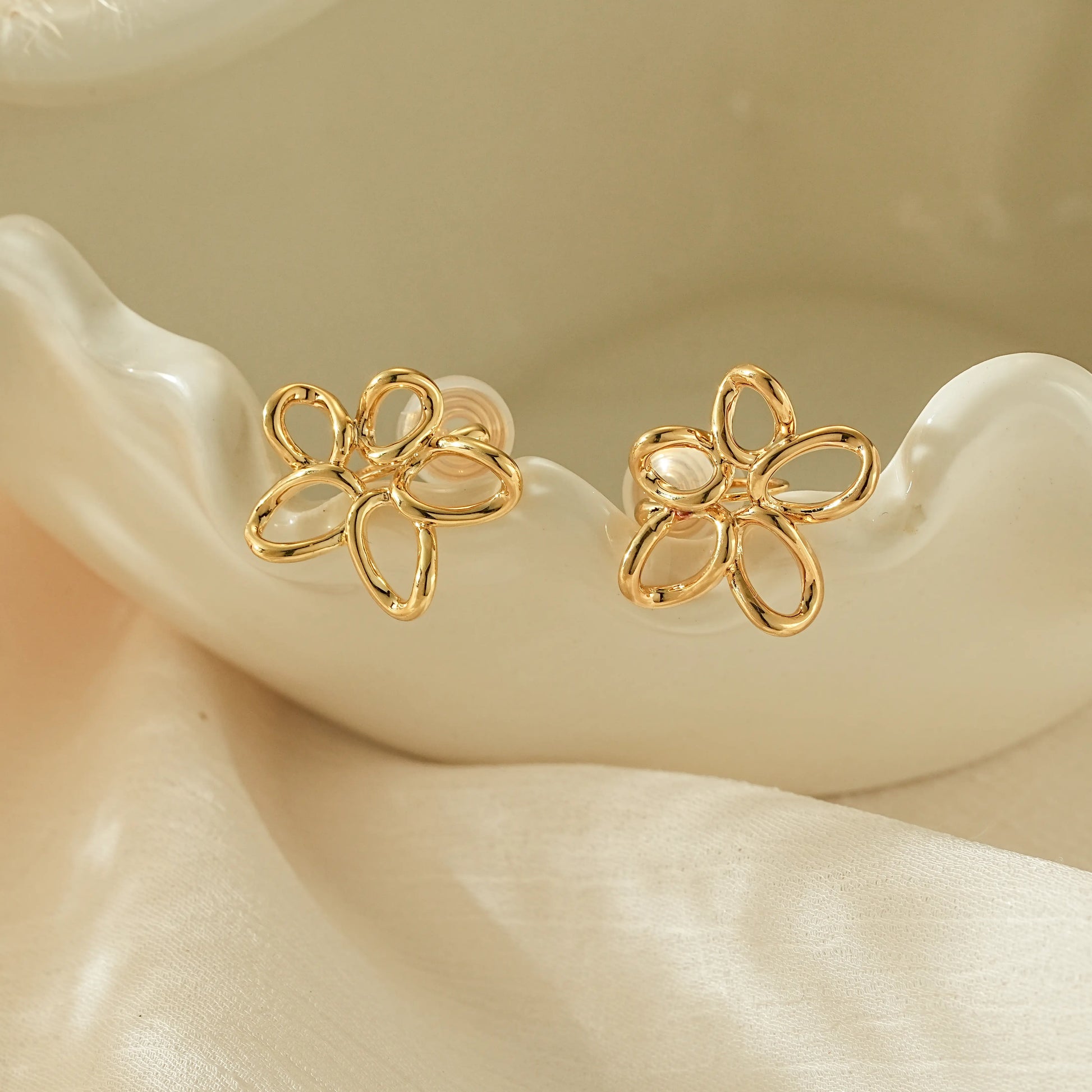 Close-up of the hand-twisted gold wire petal detail on minimalist clip-on earrings.