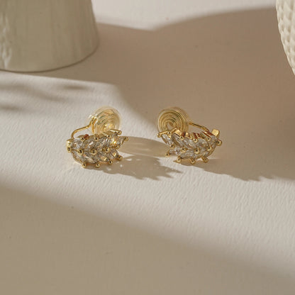 Pair of gold wheat diamond earrings on a warm, creamy boutique-style background.