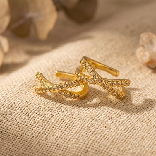 Gold ear cuffs with diamond on a beige fabric background