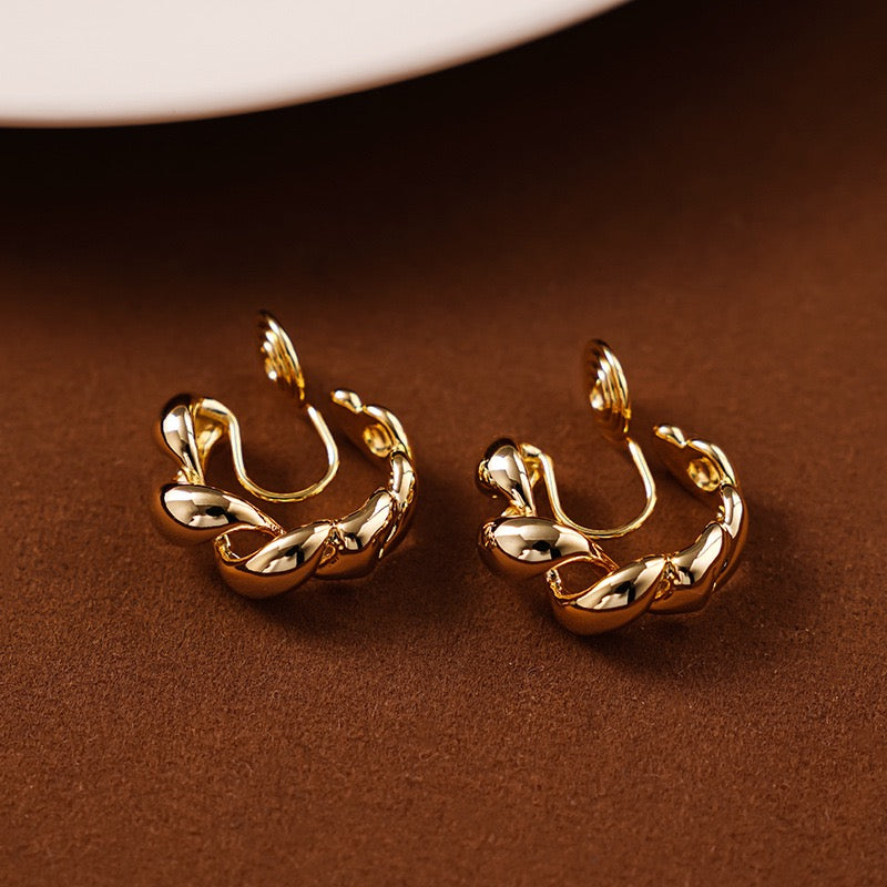 Macro close-up of the adjustable spiral tension coil clip mechanism on the back of a gold braided hoop earring