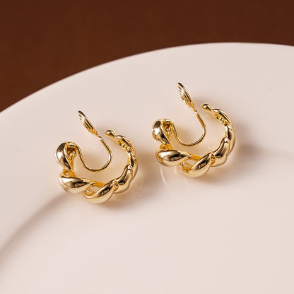 Side profile of a model styling the gold twisted hoop clip-on earrings paired with a minimalist gold ear cuff for a no-piercing ear stack.
