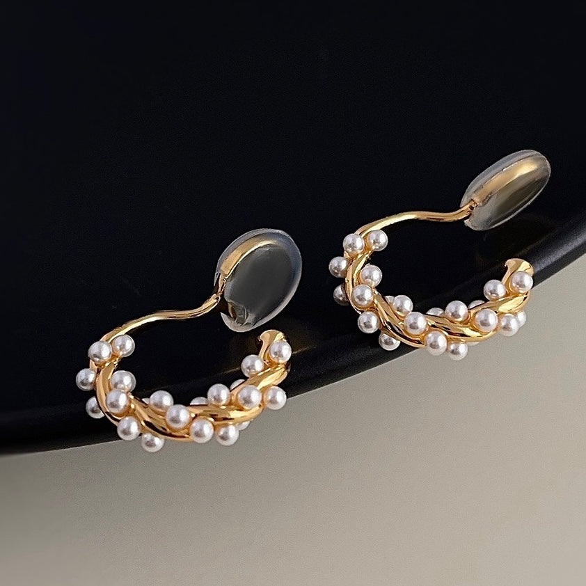 Macro close-up showing the intertwined pearls and textured gold finish of the hoop earring.
