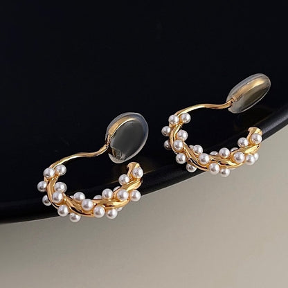 Macro close-up showing the intertwined pearls and textured gold finish of the hoop earring.