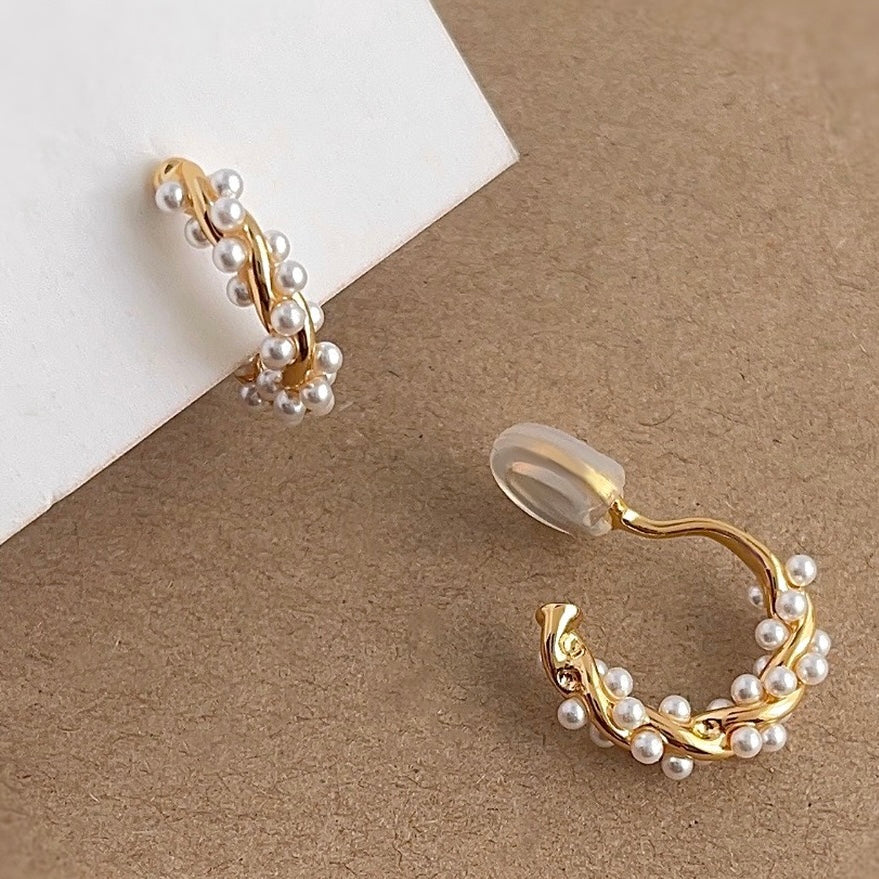 Gold pearl twisted hoops resting aesthetically on a soft velvet Earclipse branded pouch.