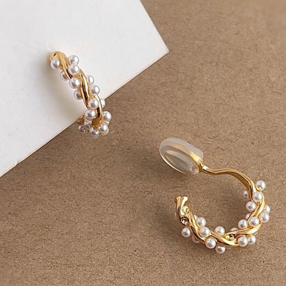 Gold pearl twisted hoops resting aesthetically on a soft velvet Earclipse branded pouch.