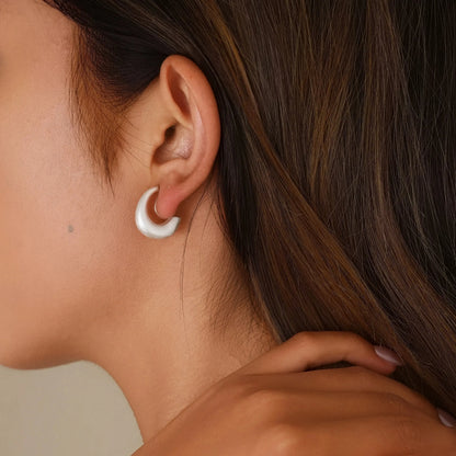 Close-up of model styling brushed silver clip-ons, showing the realistic "pierced" fit.