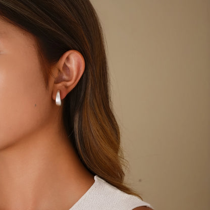 Model wearing matte silver minimalist hoops for a sophisticated, modern office look.