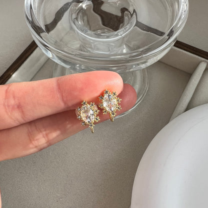 Close up of oval diamond simulant stud earring resting on a fingertip to show realistic size and dainty scale