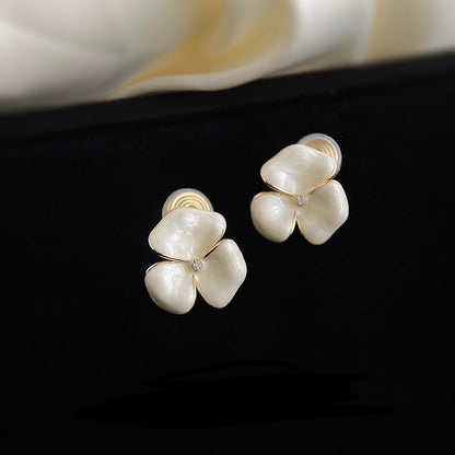 Macro close-up highlighting the glowing enamel finish, delicate gold borders, and sparkling cubic zirconia centre of the white flower earring