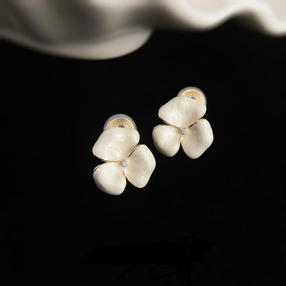 Delicate white flower earrings styled aesthetically next to a fresh cup of tea and a silk ribbon for a soft, feminine vibe