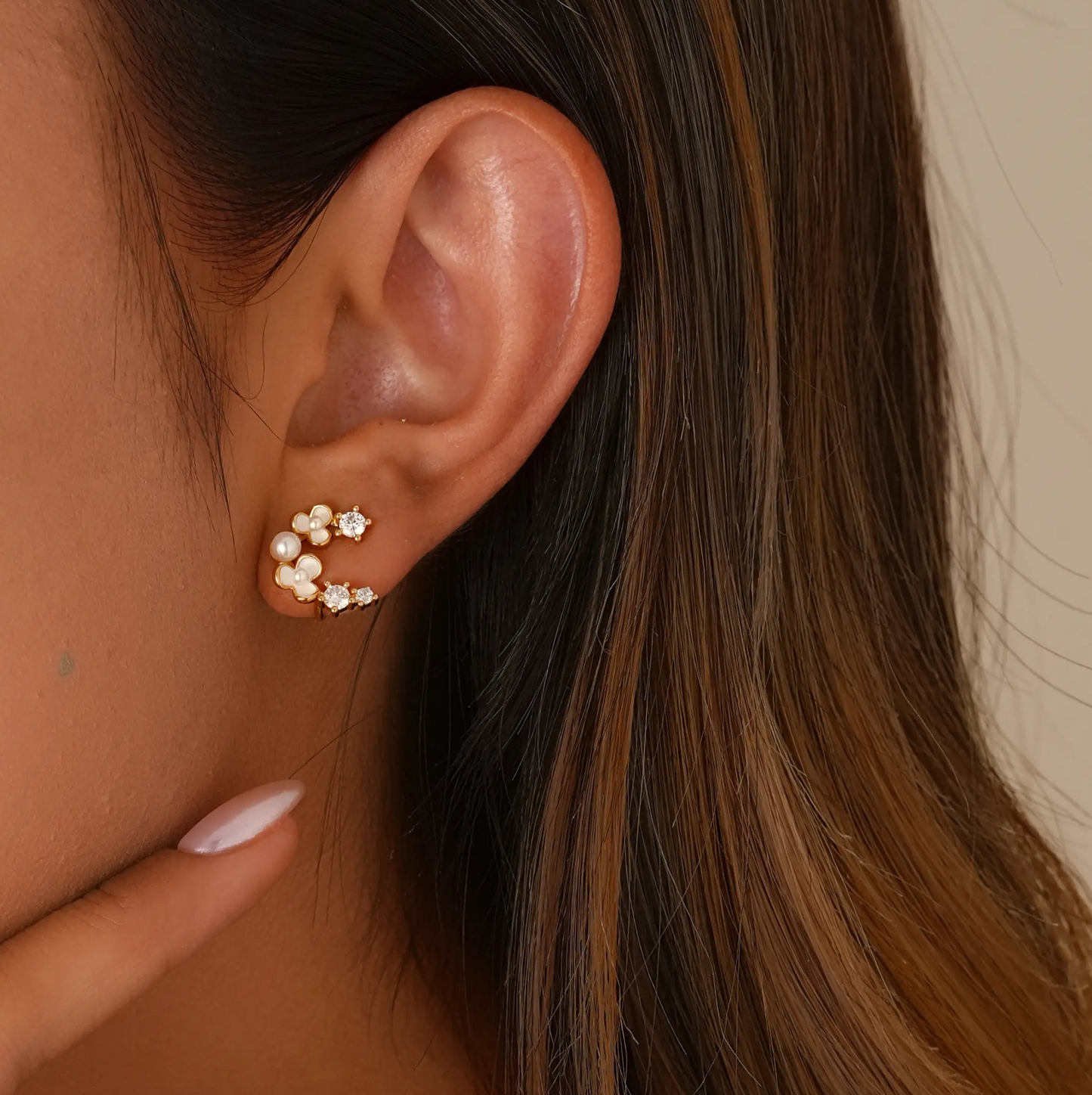 Close-up of model styling the tiny floral clips, showing a realistic "pierced" stud fit.