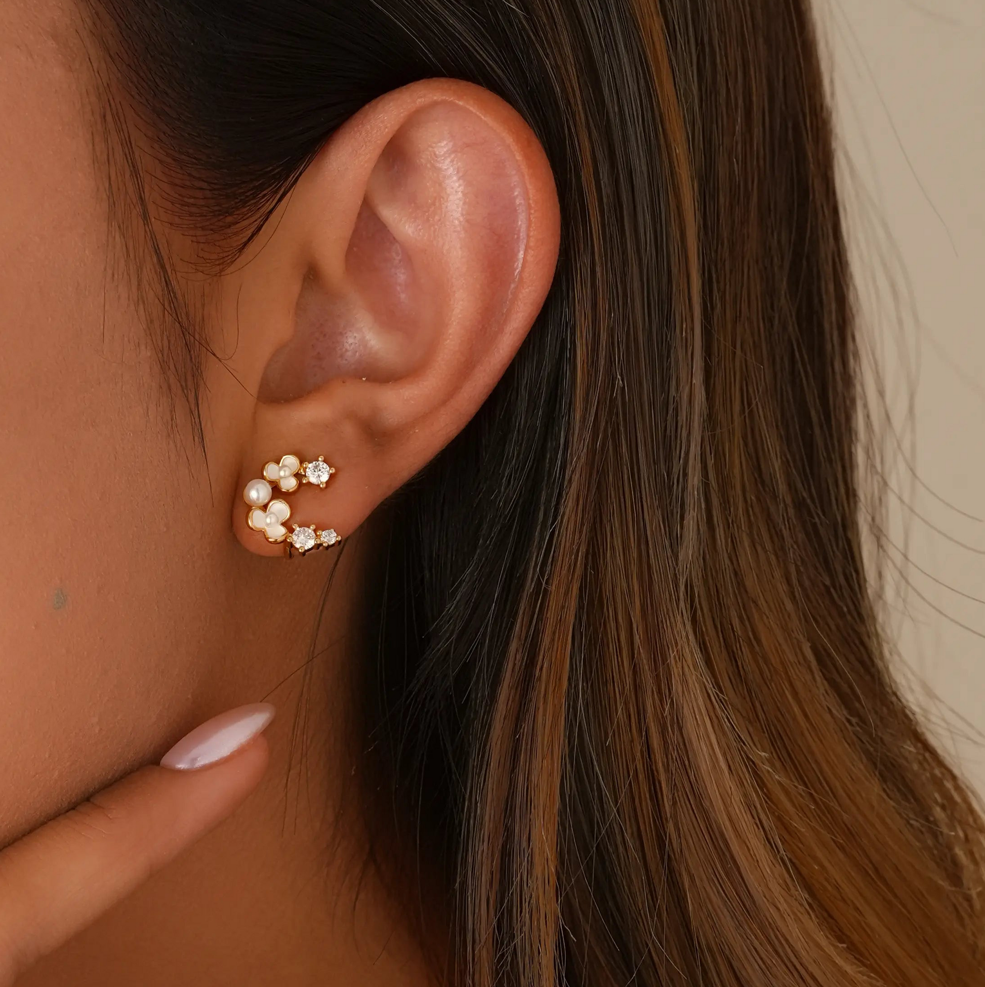 Close-up of model styling the tiny floral clips, showing a realistic "pierced" stud fit.